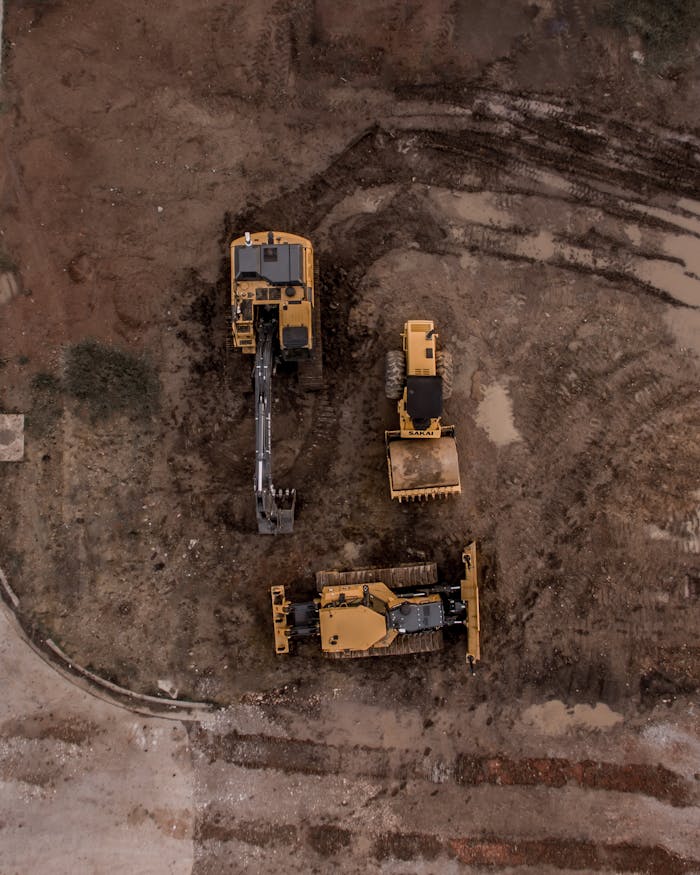 why-choose-me-02 An aerial shot of heavy machinery at a construction site, including excavators and road rollers.