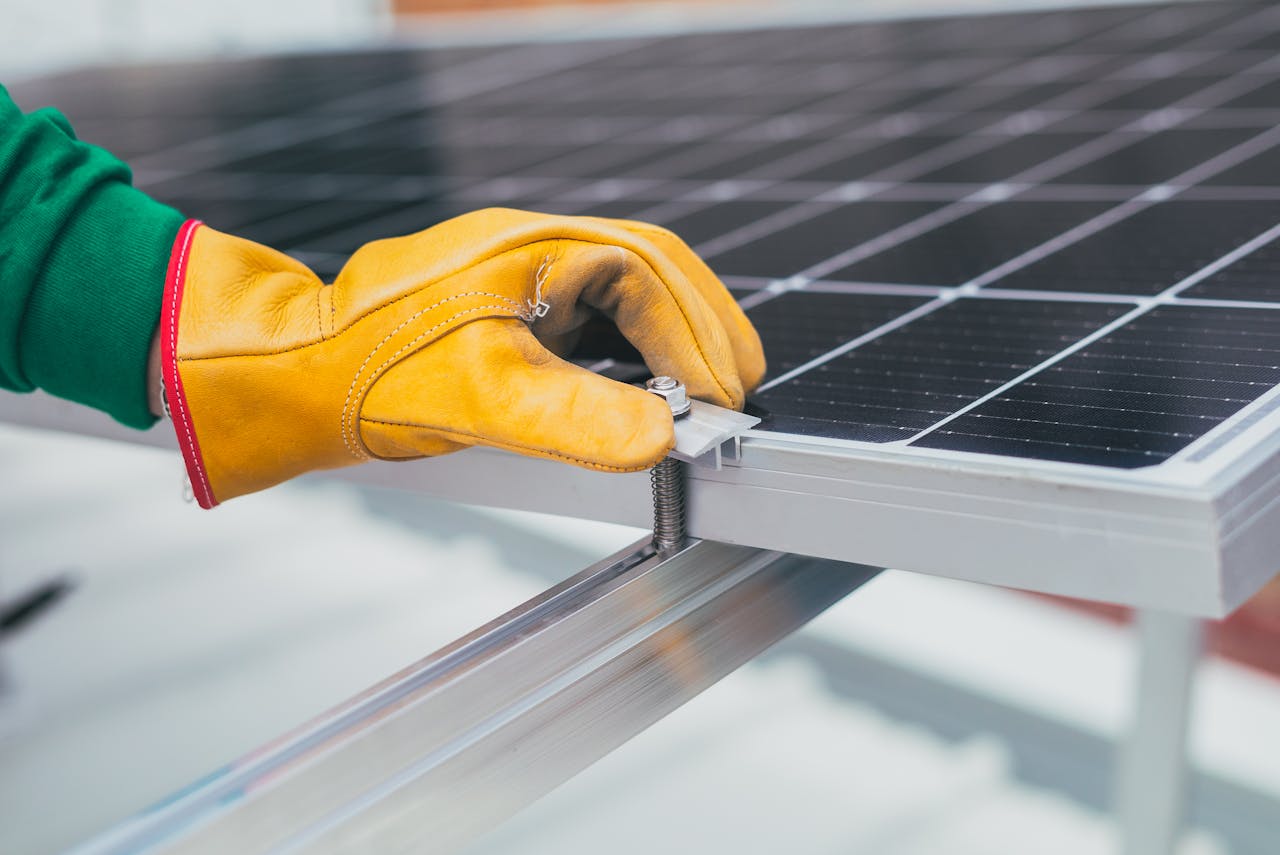 about-me-02 Close-up of a worker's hand with protective gloves adjusting a bolt on a solar panel.